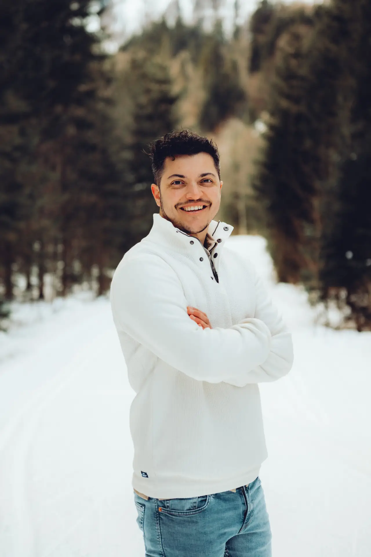 Markos Leon im weißen Pullover in einer verschneiten Winterlandschaft